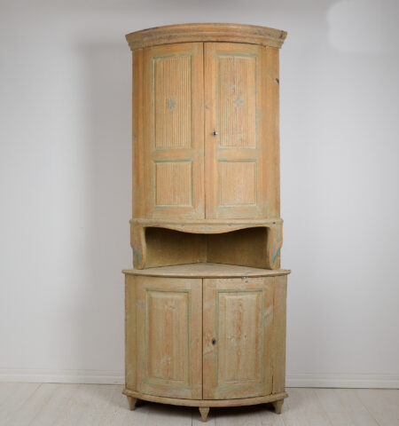 Antique Swedish corner cabinet in gustavian style. The cabinet is in two parts and most likely made during the early 1800s. Rounded shape with classic gustavian fluted doors.