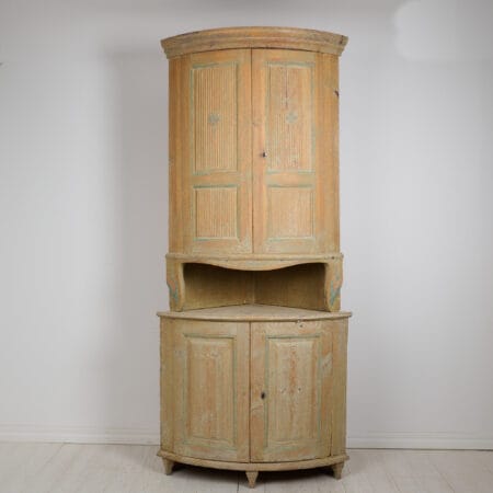 Antique Swedish corner cabinet in gustavian style. The cabinet is in two parts and most likely made during the early 1800s. Rounded shape with classic gustavian fluted doors.